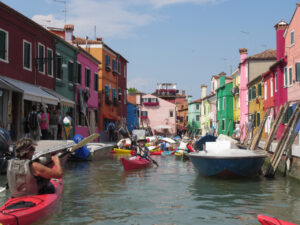 Kayaking through a canal bordered by colorful pastel buildings